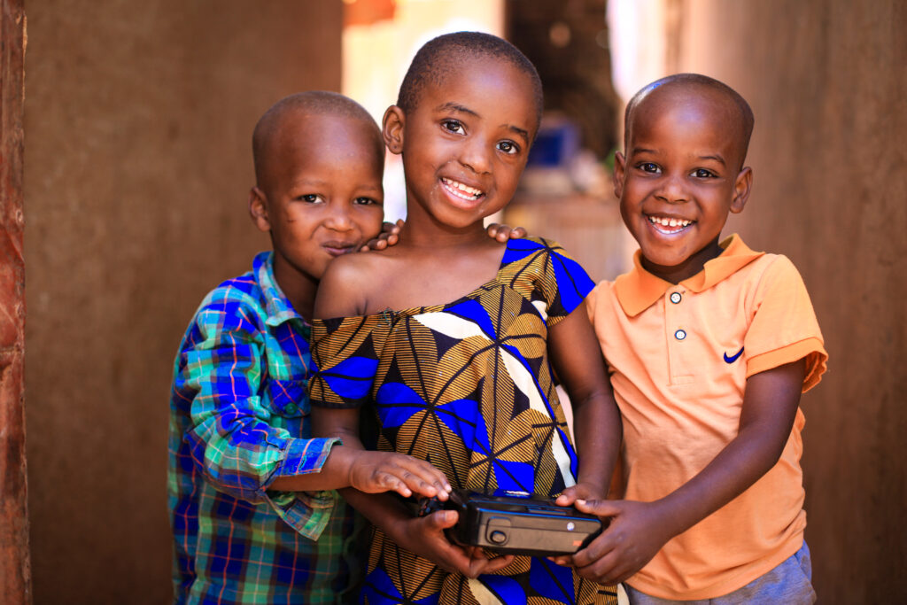 three children stand together facing the camera and smiling